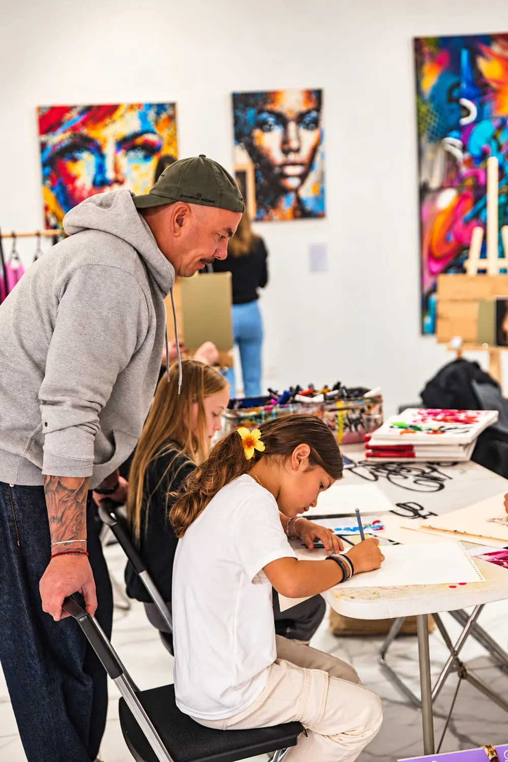 L'artiste AFRO conseille deux enfants pendant un atelier dessin au [POD]