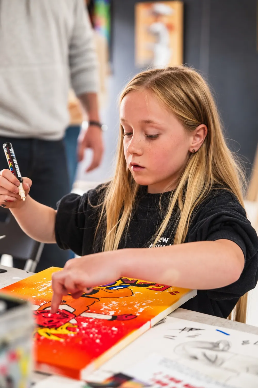 Une enfant termine sa toile pop art aux marqueurs Posca
