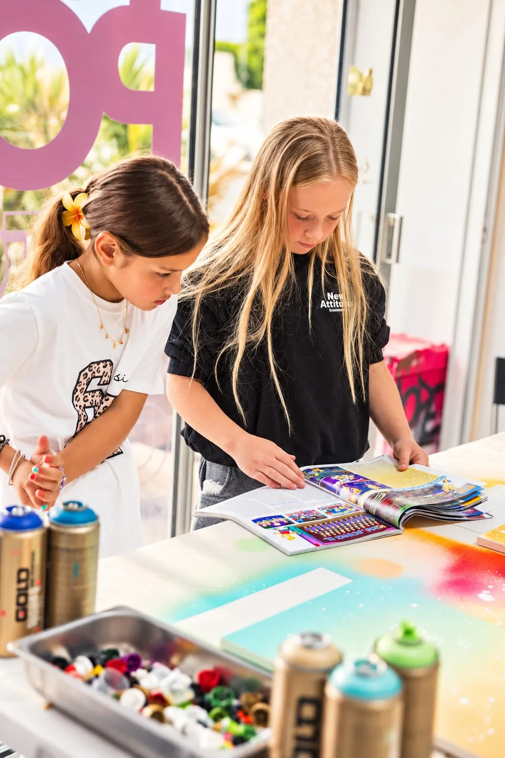 Deux enfants cherchent l'inspiration dans un magazine avant de peindre