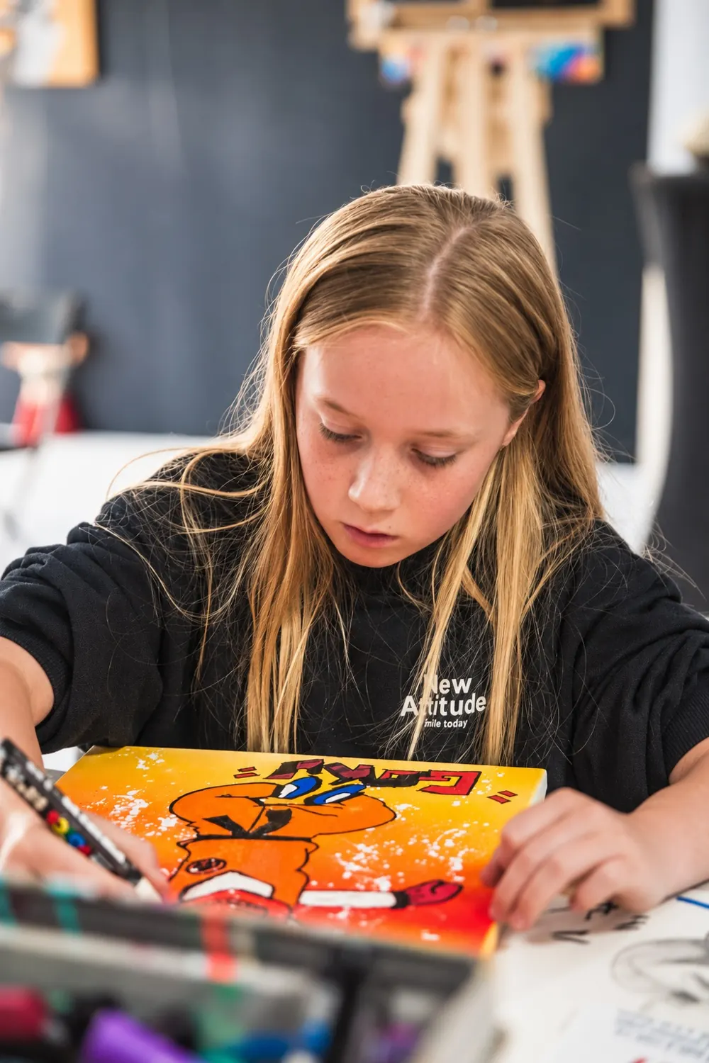 Une enfant colorie au Posca son personnage pop art sur toile, au [POD] à Muret